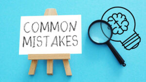 Words 'common mistakes' written on a white posterboard next to a magnifying glass against a teal background